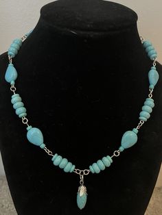 This beautiful necklace was made with turquoise colored beads. The pendant is also turquoise with stainless steel detailing. Measures 9 1/2 inches in length including the pendant. Turquoise Beaded Dangle Necklaces, Turquoise Beaded Chain Necklace With Dangle, Adjustable Turquoise Necklace With Dangling Beads, Turquoise Teardrop Beaded Chain Jewelry, Turquoise Teardrop Jewelry With Beaded Chain, Turquoise Gemstone Beads Dangle Necklace, Turquoise Teardrop Beaded Jewelry, Turquoise Dangle Necklaces With Gemstone Beads, Beaded Turquoise Howlite Necklace