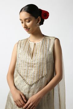 Beige kurta with gota embroidery in gold, silver stripe pattern. Paired with pant.
Components: 2
Pattern: Embroidery
Type Of Work: Gota, stripe
Neckline: Keyhole
Sleeve Type: Sleeveless
Fabric: Silk Tissue
Color: Beige
Other Details: 
Layered kurta
Disclaimer: While the designer strives to recreate every piece as close to what is displayed on the website, there may be subtle variations in color and design. If you have any concerns about the textile, kindly contact the customer service
Occasion: Elegant Sleeveless Kurta With Dupatta, Elegant Sleeveless Designer Kurta, Elegant Gold Sleeveless Sets, Elegant Sleeveless Kurta For Transitional Season, Traditional Sleeveless Kurta With Gota Work, Gold Cotton Silk Sets With Mirror Work, Elegant Sleeveless Traditional Wear With Cutdana, Traditional Gold Sleeveless Set, Elegant Gold Tops With Cutdana