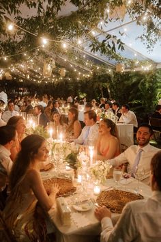 a group of people sitting around a table with food and candles in front of them