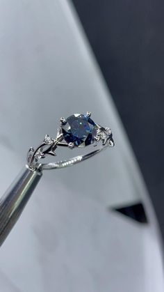 a blue diamond ring sitting on top of a piece of silver metal with diamonds around it