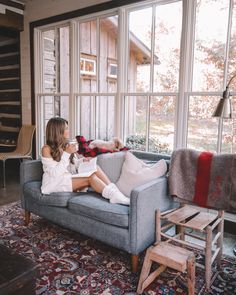 a woman sitting on top of a couch next to a window