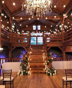 the inside of a large wooden building with chandeliers and lights hanging from the ceiling