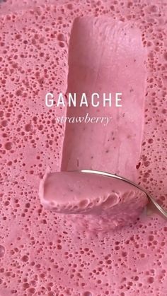 a spoon is on top of a pink substance with the word ganache in it