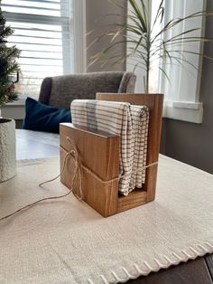 a wooden box sitting on top of a table next to a potted pine tree