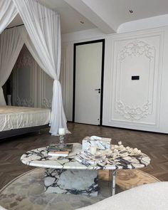 a white bed sitting next to a glass table on top of a hard wood floor