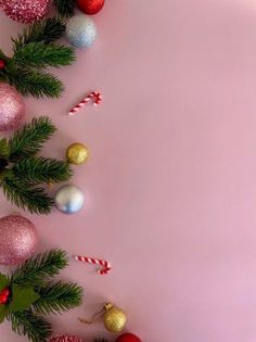 christmas ornaments and candy canes on a pink background