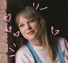 a woman with pink arrows drawn on her face next to a brick wall and looking at the camera