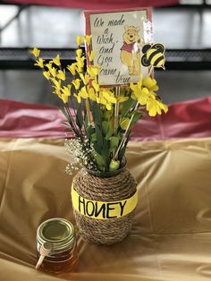 a vase filled with yellow flowers next to a jar of honey and a sign that says honey