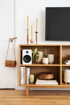 an entertainment center with books, plants and other things on it in front of a flat screen tv