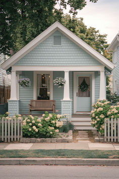 a blue house with white trim and flowers in front