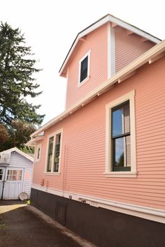 a pink house with white trim on the front and side of it's windows