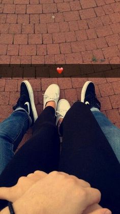 two people standing next to each other on a brick walkway with a red heart in the middle