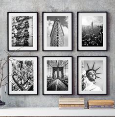 four black and white pictures hanging on the wall above a table with books, vase and plant