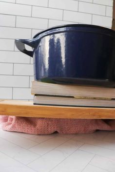 a stack of books sitting on top of a wooden shelf next to a blue pot