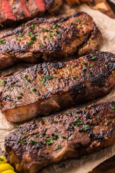 some steaks are sitting on top of parchment paper next to yellow and green flowers