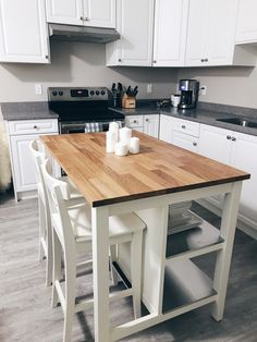 a kitchen with white cabinets and wooden counter tops in front of a stove top oven