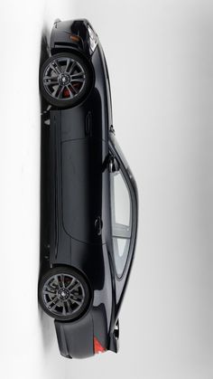 an overhead view of a black car with its wheels on the rims hanging from a white wall