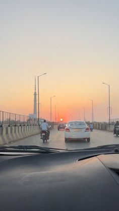 the sun is setting behind some cars on the road