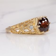 This gorgeous ring features a rich red spinel paired with a romantic, vintage style setting! The round cut spinel center has a deep and highly saturated red hue! The 14k yellow gold setting is studded with diamonds and beautifully embellished with curling filgree. The effect is classic, graceful, and sweetly feminine.The 2.56ct spinel is vibrantly saturated with very rich color. It is eye clean, luminous, and dimensional, displaying a beautiful play of light and color. The accent diamonds are br Elegant Yellow Gold Ruby Ring With Intricate Design, Luxury Ruby Ring With Gemstone Accents For Anniversary, Victorian Wedding Jewelry With Gemstone Accents, Gold Rings With Rose Cut Diamonds And Garnet, Gold Garnet Ring With Rose Cut Diamonds, Gold Heirloom Ruby Ring With Gemstone Accents, Heirloom Gold Ruby Ring With Gemstone Accents, Vintage Diamond Rings With Gemstone Accents, Vintage Garnet Ring With Center Stone