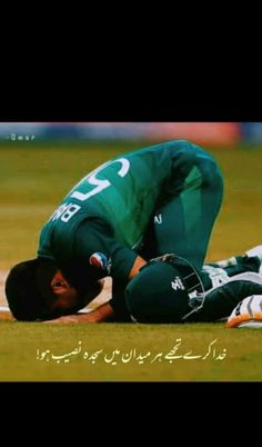 a man laying on the ground with his head in his hands while wearing a green uniform