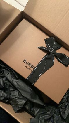 an open box with a black ribbon on it