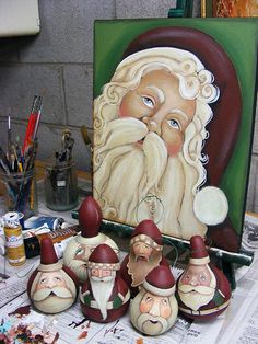 a group of santa claus figurines sitting on top of a table next to a painting