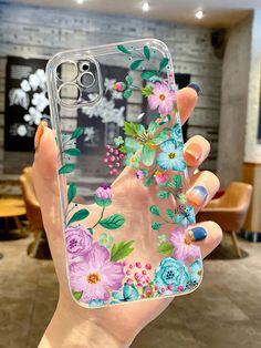 a woman holding up her phone case with flowers on it