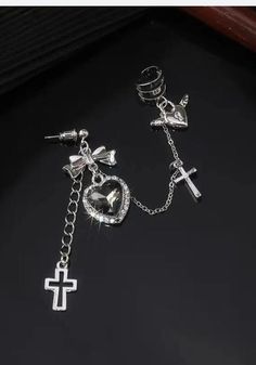 Embrace the goth aesthetic with our Heart Cross Chain Earrings. Featuring a black heart-shaped stone with a cross and bow, along with heart with wings accessory details. The combination with an ear cuff adds an extra edge to these zinc alloy earrings, creating a cool and unique style. Goth aesthetic Black heart shaped stone design with cross & bow Heart with wings accessory details Combined with ear cuff Zinc alloy Package: 1 piece Y2k Grunge Aesthetic, Cross Bow, Gothic Heart, Hip Hop Fashion 90s, Goth Earrings, Aesthetic Jewelry, Heart With Wings, Cross Chain, Alloy Earrings