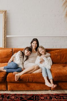 three women sitting on a couch with their arms around each other