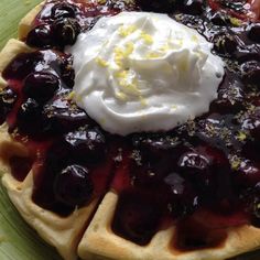 a waffle topped with whipped cream and cherries on a green platter,