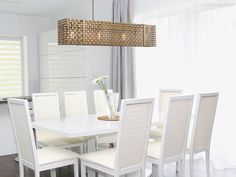 a dining room table with white chairs and a chandelier