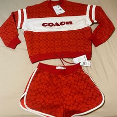 a red and white soccer uniform with the word coach on it's chest, sitting on a bed