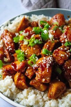 a bowl filled with rice and chicken covered in sesame seeds, green onions and sauce