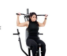 a woman sitting on top of a stationary exercise bike while holding onto the barbells