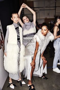 three models pose for the camera in front of an audience