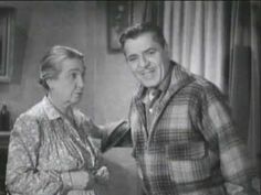 an old black and white photo of a man standing next to a woman in a plaid shirt