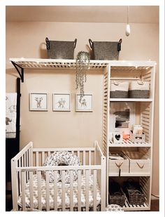 a baby's crib in the corner of a room next to a wall with pictures on it