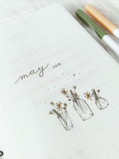 an open notebook with three vases on it and the words may written in cursive writing