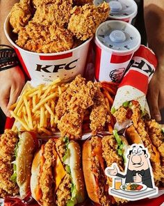 a large platter filled with chicken sandwiches and fries next to two cups of soda