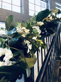 flowers and greenery on the railing of a building