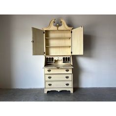 an old fashioned kitchen cabinet with cupboards and drawers on the bottom, in front of a gray wall