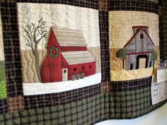 three quilts are hanging on the wall in front of each other, one has a barn and two houses