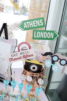 a table topped with lots of signs and desserts next to a glass window covered in snow