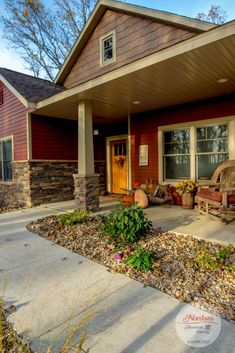 the front porch of a house with flowers and plants on the ground in front of it