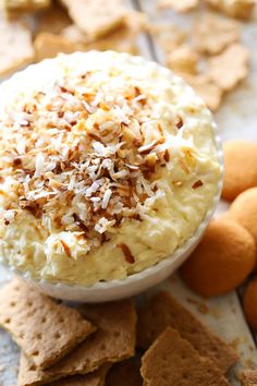 a close up of a bowl of food with nuts on the side and crackers in the background