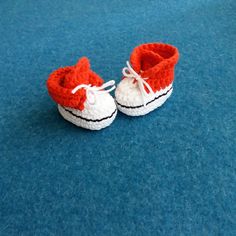 there is a pair of crocheted baby shoes on the blue carpeted floor