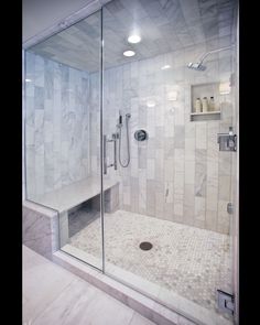 a walk in shower sitting next to a white tiled wall and floor with glass doors