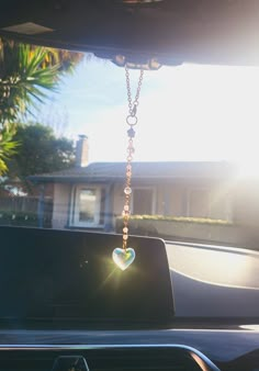 the sun shines brightly through the windshield of a car with a heart hanging from it