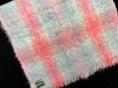 a pink and white plaid blanket on a black background