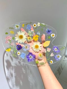 a person holding a glass plate with flowers on it